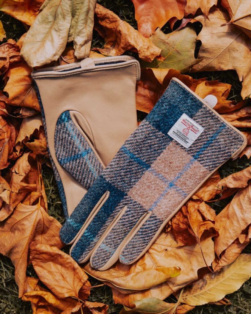 Islander leather and Harris Tweed gloves in navy and cream, lying on autumn leaves