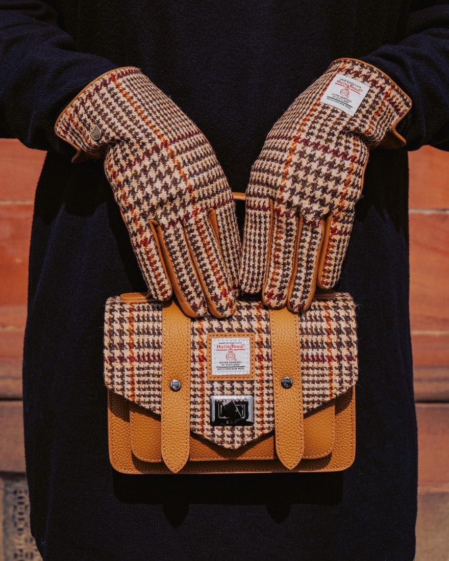Harris Tweed mini satchel in a brown check with tan leather straps, held by gloved hands